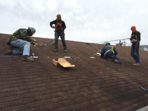 People on a roof of a home in appalachia. Coalfield development corporation does construction