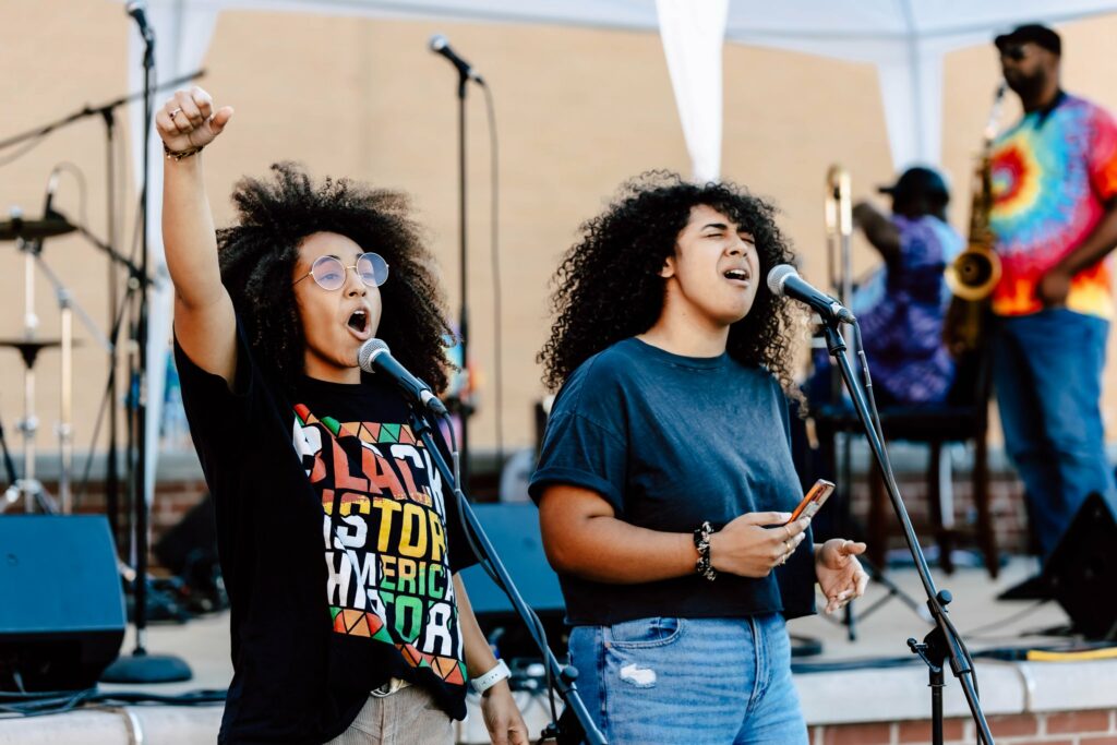 Two people stand in front of a microphone