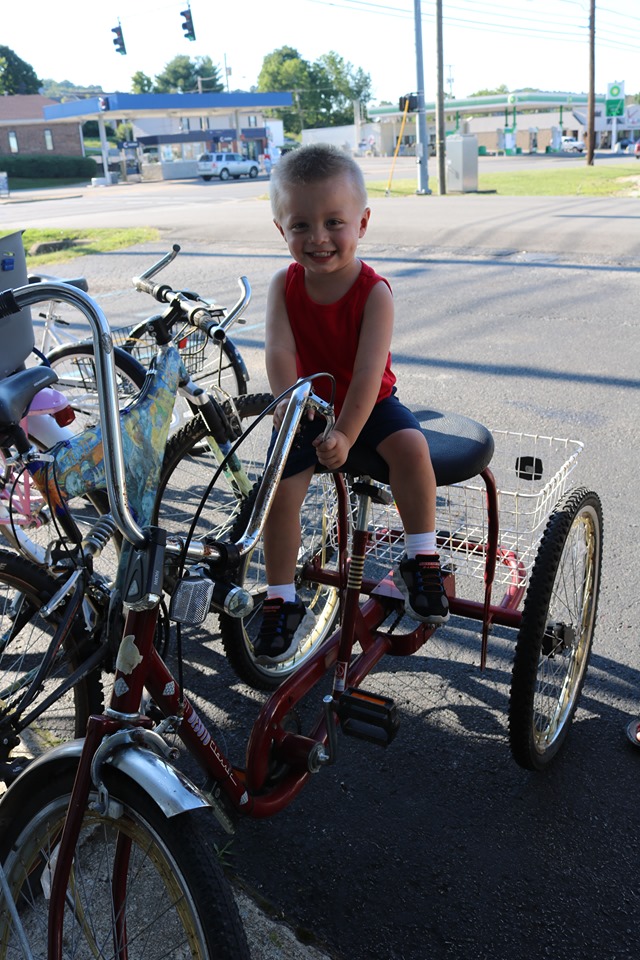 a young kid sits on a special bike outside of grayson art gallery in carter county, kentucky. A rural area where many do not have cars