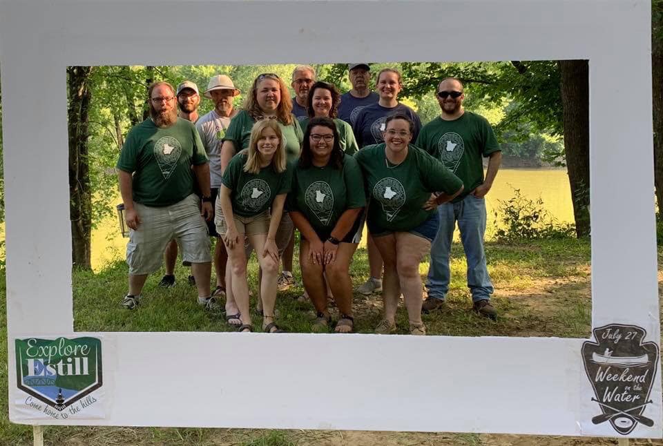 A group stands inside a frame at an explore estill event. The event was to celebrate their hiking, biking and paddling trails in eastern kentucky