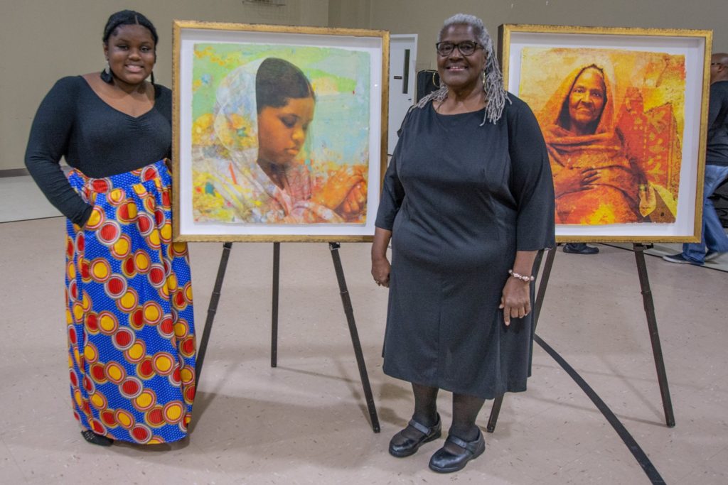 Two women pose with Winchester Kentucky portraits as part of the I was here exhibit