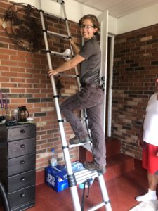Woman stands on a ladder during an energy efficiency audit in eastern kentucky.