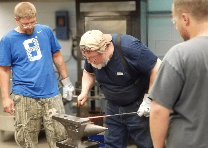 Two people watch a blacksmith artist during a class in knott county, kentucky. The class is part of the culture of recovery for addiction